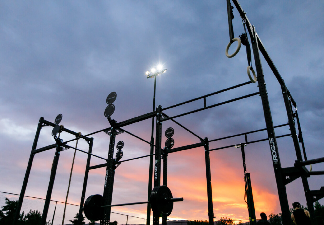Outdoor-Fitnessrig bei Sonnenuntergang mit Hanteln, Ringen und Trainingsstationen